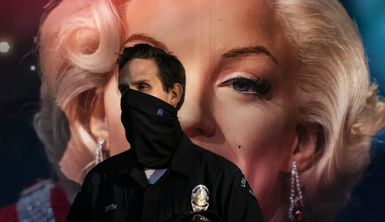 Polisi mengenakan penutup wajah saat berdiri depan iklan yang menampilkan Marilyn Monroe di bagian Hollywood Los Angeles, California, AS, Kamis (12/11/2020). California, AS, Kamis (12/11/2020). California menjadi negara bagian kedua yang mencatat 1 juta kasus infeksi COVID-19. (AP Photo/Jae C. Hong)