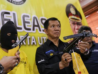 Petugas menujukan senjata api dan panah tembak saat rilis di Polres Jakarta Utara, Senin (25/1). Dalam penggrebekan petugas berhasil menyita 20,74 Gram Sabu, sejumlah senjata api berikut amunisi dan sebuah granat nanas aktif. (Liputan6.com/Faizal Fanani)