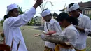 Seorang pemuka agama mencipratkan air suci pada beberapa warga Bali yang mendatangi pura di Jimbaran, Bali, Rabu (21/5/14). (AFP PHOTO/Sonny Tumbelaka)