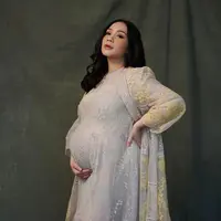 Nagita Slavina tampil anggun pancarkan pesona bumil dengan long tulle bernuansa abu-abu. Tampilannya semakin terlihat memesona dengan tambahan outer brokat kuning. (Instagram/raffinagita1717).