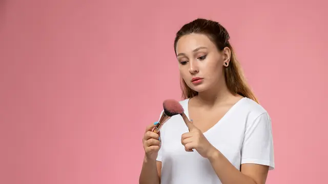 Seorang perempuan sedang memegang sebuah brush make up (Foto Dok: Freepik/KamranAydinov)