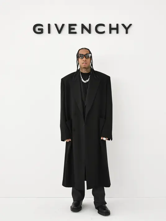 Tyga memadukan overized look dengan t-shirt, coat, dan kalung rantai [Givenchy]