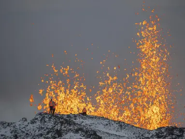 Ilmuwan dari Universitas Islandia melakukan pengukuran dan sampel dengan berdiri di punggung bukit di depan bagian aktif celah letusan gunung berapi aktif di Grindavik di Semenanjung Reykjanes Islandia, Selasa (19/12/2023). (AP Photo/Marco Di Marco)