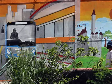 Pekerja berjalan di depan mural Kota Jakarta, Tanah Kusir, Kebayoran Lama, Jakarta, Jumat (26/11/2021). Mural tersebut bertemakan Kota Jakarta dengan gambar ikon seperti ondel-ondel, Monas hingga transportasi. (Liputan6.com/Herman Zakharia)