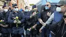 Petugas polisi memegang bunga yang diberikan demonstran selama aksi protes di Circus Maximus Roma, Jumat (15/10/2021). Protes tersebut karena aturan yang mengharuskan seluruh pekerja di Italia menunjukkan kartu kesehatan covid-19 untuk memasuki tempat kerja mereka. (AP Photo/Gregorio Borgia)