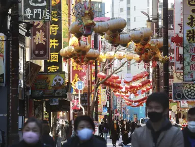 Orang-orang yang memakai masker berjalan di bawah pernak-pernik Imlek saat melintasi Chinatown di Yokohama, Prefektur Kanagawa, dekat Tokyo, Selasa (9/2/2021). Yokohama Chinatown adalah kawasan pecinan terbesar di Jepang, terletak di pusat kota Yokohama. (AP Photo/Koji Sasahara)