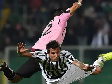 Pemain Juventus, Mario Mandzukic (kanan) berduel udara dengan pemain Palermo pada lanjutan Liga Italia Serie A  di Stadion Renzo Barbera, Palermo, Senin (30/11/2015) dini hari WIB .  (AFP Photo/Gabriel Bouys)