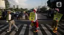 Angggota Komunitas Aku Badut Indonesia (ABI) melakukan aksi kampanye penggunaan di kawasan Cilandak, Jakarta Selatan, Senin (12/7/2021). Selain itu, mereka juga membagi-bagikan masker secara gratis bagi para pengendara motor yang melintas. (Liputan6.com/Johan Tallo)