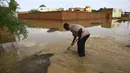 Seorang pria bekerja di tengah genangan banjir di Khartoum, Sudan (3/8/2020). Sudan dilanda banjir baru-baru ini akibat hujan lebat. (Xinhua/Mohamed Khidir)