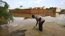 Seorang pria bekerja di tengah genangan banjir di Khartoum, Sudan (3/8/2020). Sudan dilanda banjir baru-baru ini akibat hujan lebat. (Xinhua/Mohamed Khidir)
