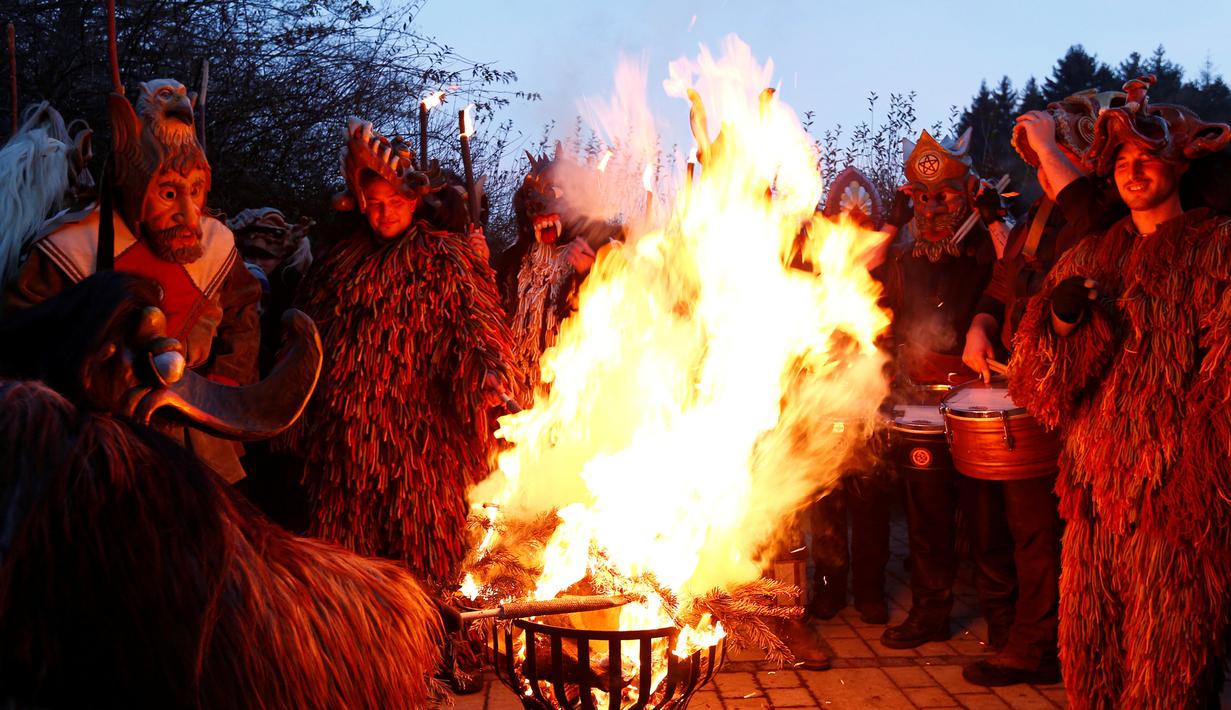 Para peserta mengenakan kostum iblis membuat api unggun saat parade tardisional Perchtenlauf di Osterseeon dekat Munchen, Jerman (17/12). Tradisi ritual Pagan ini telah berusia 1.500 tahun (Reuters/Michaela Rehle)