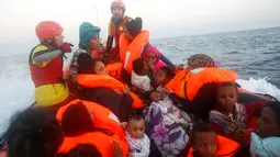 Sejumlah wanita dan balita terombang-ambing di kapal kayu yang disesaki puluhan imigran, di lepas panti Libya, Laut Mediterania, Senin (29/8). Penjaga pantai Italia berhasil menyelamatkan 6.500 imigran dari Eritrea dan Somalia. (REUTERS/Giorgos Moutafis)