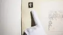 Petugas menunjuk ke prangko pertama di dunia, Penny Black, yang dipajang menjelang lelangnya, di Sotheby Hong Kong, Selasa (26/10/2021). Penny Black merupakan prangko berperekat pertama di dunia yang menampilkan sosok Ratu Victoria dan tercetak dengan background warna hitam. (ISAAC LAWRENCE / AFP)