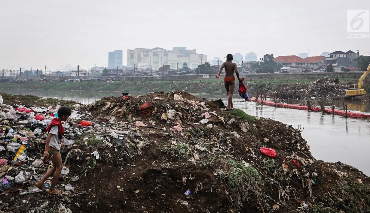 Anak- anak mengenakan pakaian usai mencari biawak di tepi Sungai Banjir Kanal Barat, Petamburan, Jakarta, Jumat (9/11). Mereka memanfaatkan waktu bermain usai pulang sekolah. (Liputan6.com/Fery Pradolo)