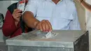 Calon Walikota Depok, Mohammad Idris dan istri memasukkan surat suara kedalam kotak di TPS 077 di Perum Pondok Duta, Sukmajaya, Depok, (9/12). Mohammad Idris diusung oleh Partai Keadilan Sejahtera (PKS) dan Partai Gerindra. (Liputan6.com/Yoppy Renato)