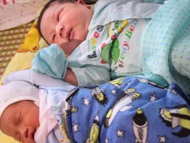 Seorang bayi laki-laki, Tran Tien Quoc (atas) sedang tidur di samping bayi laki-laki tidak dikenal di pusat kesehatan Vinh Tuong, provinsi Vinh Phuc, Minggu (15/10). Ibu asal Vietnam melahirkan bayi laki-laki itu dengan berat 7,1 kilogram. (LE PHUONG/AFP)