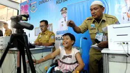 Seorang anak penderita Spina Bifida melakukan pemotretan pembuatan kartu identitas anak (KIA) di  Lapangan Skadron 21 Sena Penerbad, Tangerang Selatan, Banten (25/11/2019). Spina Bifida kelainan pada tubuh janin akibat pembentukan saraf tulang belakang yang tidak sempurna. (merdeka.com/Arie Basuki)