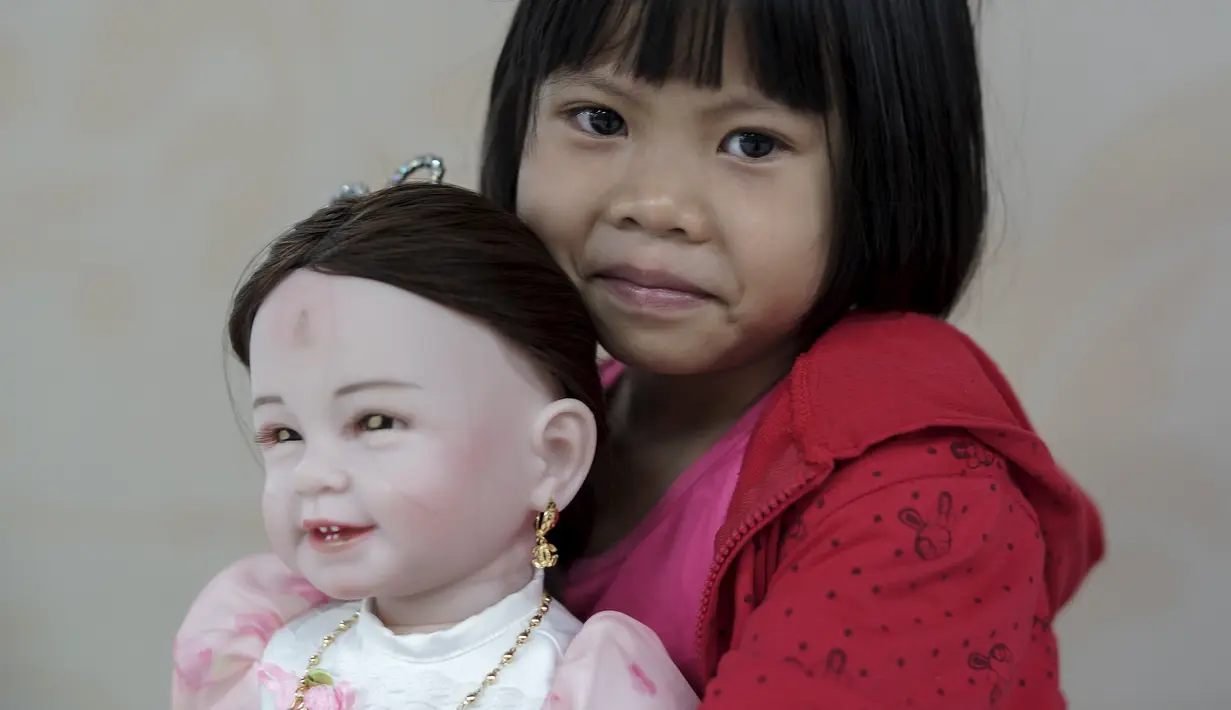 Prew menggendong boneka Look Thep (anak malaikat) di sebuah toko di department store, Bangkok, Thailand, Selasa (26/1). Boneka yang diisi dengan roh anak kecil melalui ritual tertentu itu dipercaya bisa membawa keberuntungan (REUTERS/Athit Perawongmetha)