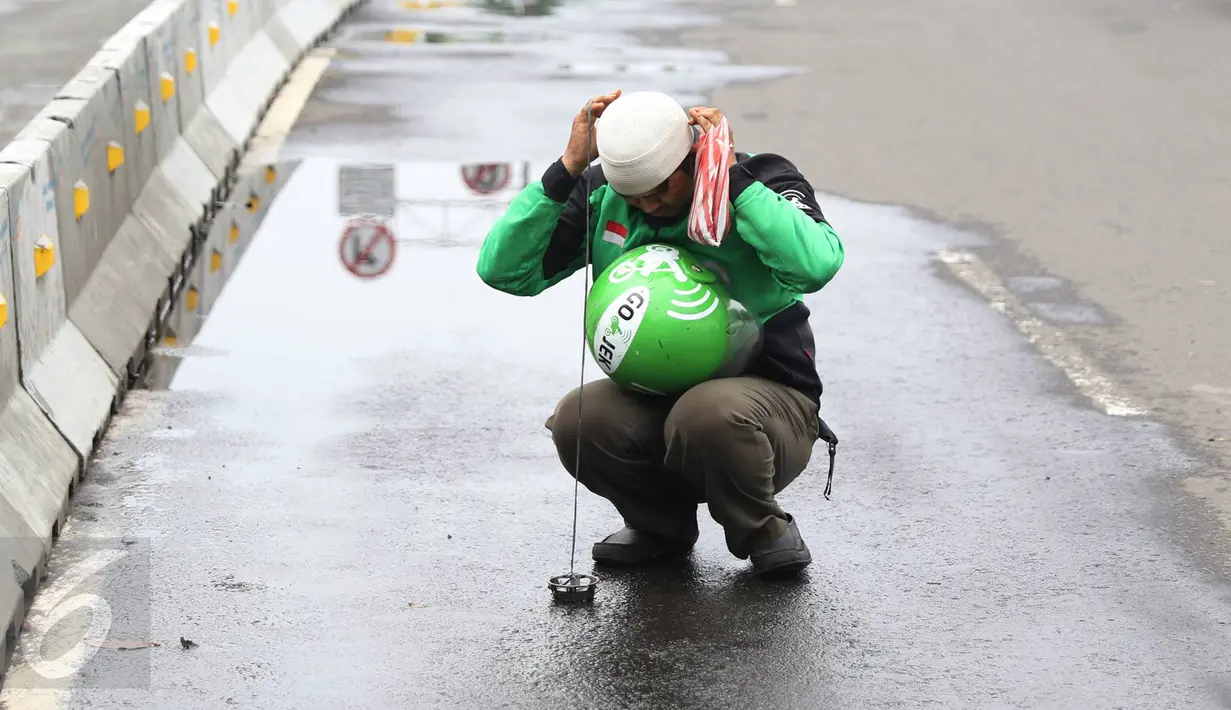 Pengendara Gojek bernama Ari mencari ranjau paku yang berserakan di sekitar Istana Negara, Jakarta, Minggu (14/8). Pria 32 tahun tersebut secara ikhlas mengumpulkan ranjau paku di sekitar Istana Negara.(Liputan6.com/Immanuel Antonius)