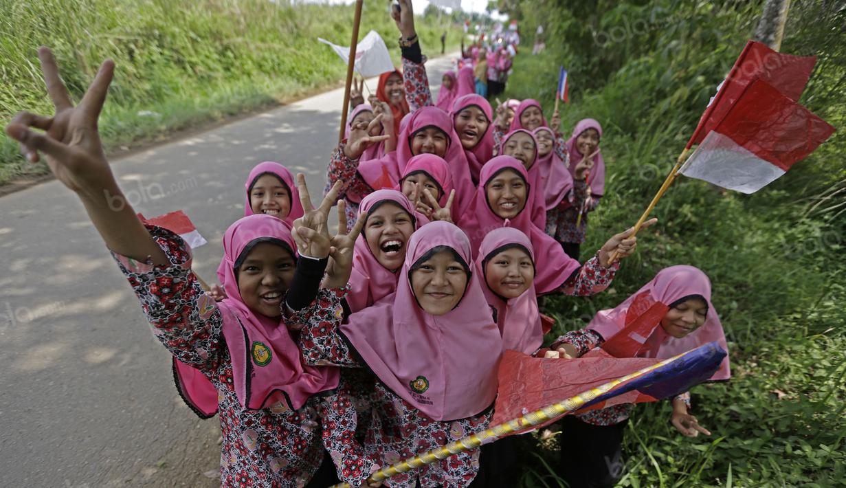 Wajah ceria anak-anak sekolah menanti para pebalap Tour de Singkarak 2016 saat menuju garis finish di Dharmasraya, Sumatera Barat, (12/8/2016). (Bola.com/Nicklas Hanoatubun)