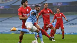 Gelandang Manchester City, Riyad Mahrez (tengah) melepaskan umpan dibawah tekanan pemain Birmingham City dalam laga babak ke-3 Piala FA 2020/21 di Etihad Stadium, Minggu (10/1/2021). Manchester City menang 3-0 atas Birmingham City. (AFP/Oli Scarff/Pool)