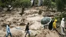 Orang-orang menyeberangi sungai yang mengamuk di Blantyre, Malawi, Senin, 13 Maret 2023. Topan Freddy yang tak henti-hentinya yang saat ini menghantam Afrika bagian selatan telah menewaskan sedikitnya 56 orang di Malawi dan Mozambik sejak melanda benua itu untuk kedua kalinya pada Sabtu malam, otoritas di kedua negara telah mengkonfirmasi. (AP Photo/Thoko Chikondi)