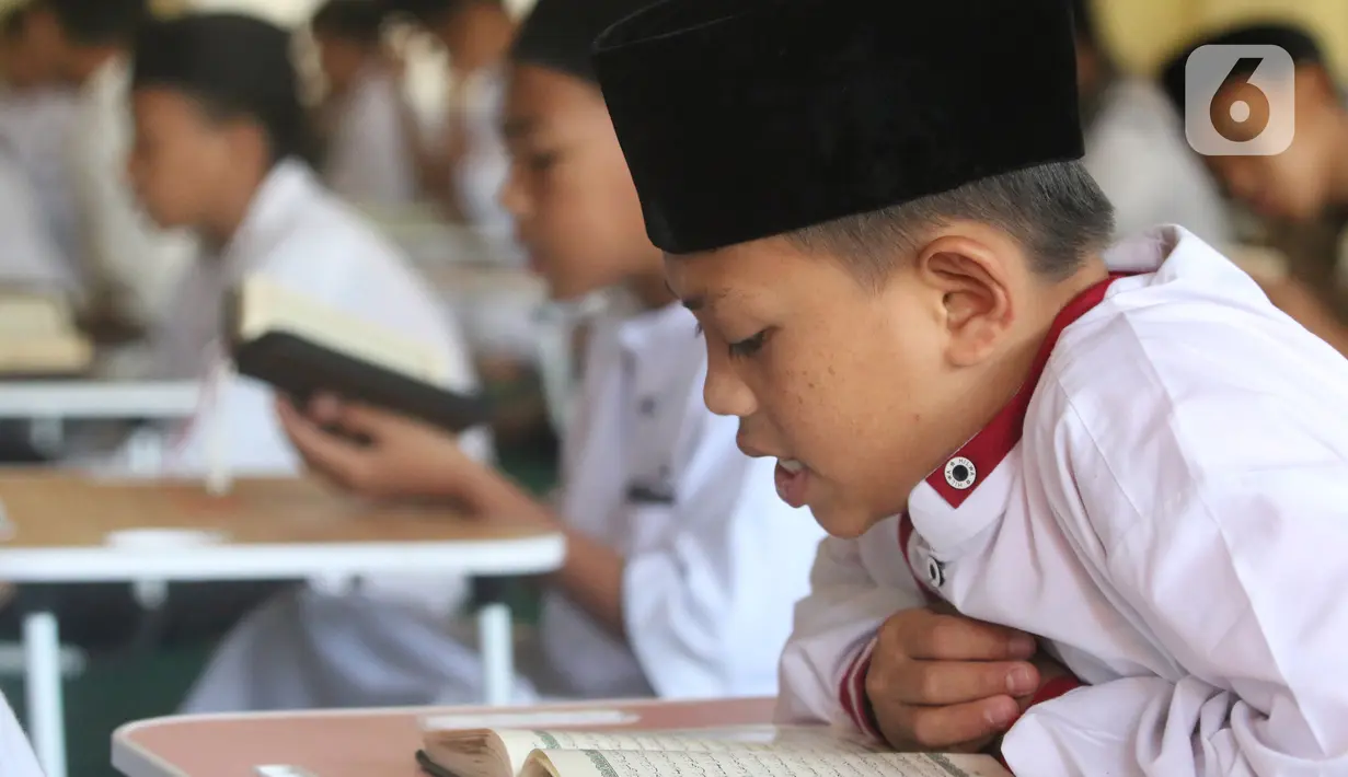 Santri yang masih berusia belasan tahun membaca Al Quran bersama-sama (tadarus) dalam rangka mengkhatamkan Qur'an dengan menerapkan jaga jarak pada Masjid Daarul Qu'ran  Pesantren Al Kautsar, Cibinong, Bogor, Jawa Barat, Minggu (10/04/2022). (merdeka.com/Arie Basuki)