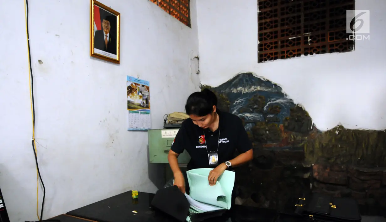Petugas mengecek dokumen di rumah terduga penampung TKI Ilegal di Jalan Percetakan Negara X, Jakarta, Rabu (31/5). Bersama satu tersangka, petugas Dirtipidum Mabes Polri melakukan pencarian barang bukti baru. (Liputan6.com/Helmi Fithriansyah)