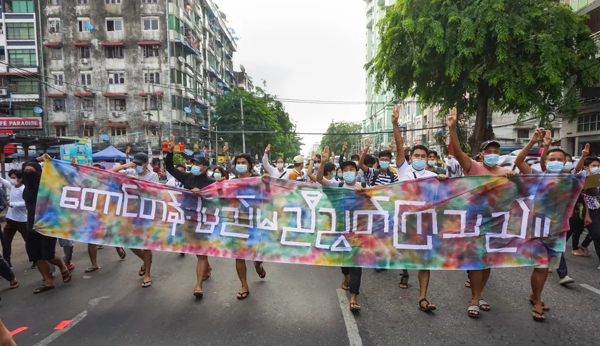 Pengunjuk rasa memberi hormat tiga jari sambil memegang spanduk bertuliskan, "Bukit dan Wilayah Tengah bersatu" di Yangon (3/6/2021). Demonstran pro-demokrasi turun ke jalan di kota-kota di Myanmar untuk mengecam militer, menandai empat bulan sejak menggulingkan pemerintah terpilih. (AFP/STR)