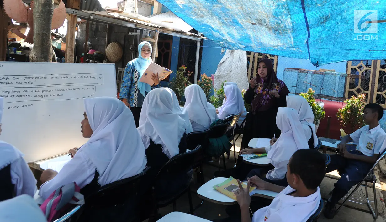 Guru mengajar siswa kelas 8 SMP  1 Cijeruk Terbuka di tempat belajar beratapkan terpal di halaman rumah warga di Kampung Cijeruk RT 002/005, Desa Palasari, Kecamatan Cijeruk, Kabupaten Bogor, Jawa Barat, Senin (2/9/2019). (merdeka.com/Arie Basuki)