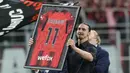 Pemain AC Milan, Zlatan Ibrahimovic, menunjukkan memorabilia kepada para suporter setelah memberikan pidato perpisahannya dari dunia sepakbola di San Siro, Senin (5/6/2023) dini hari WIB. (AP Photo/Antonio Calanni)