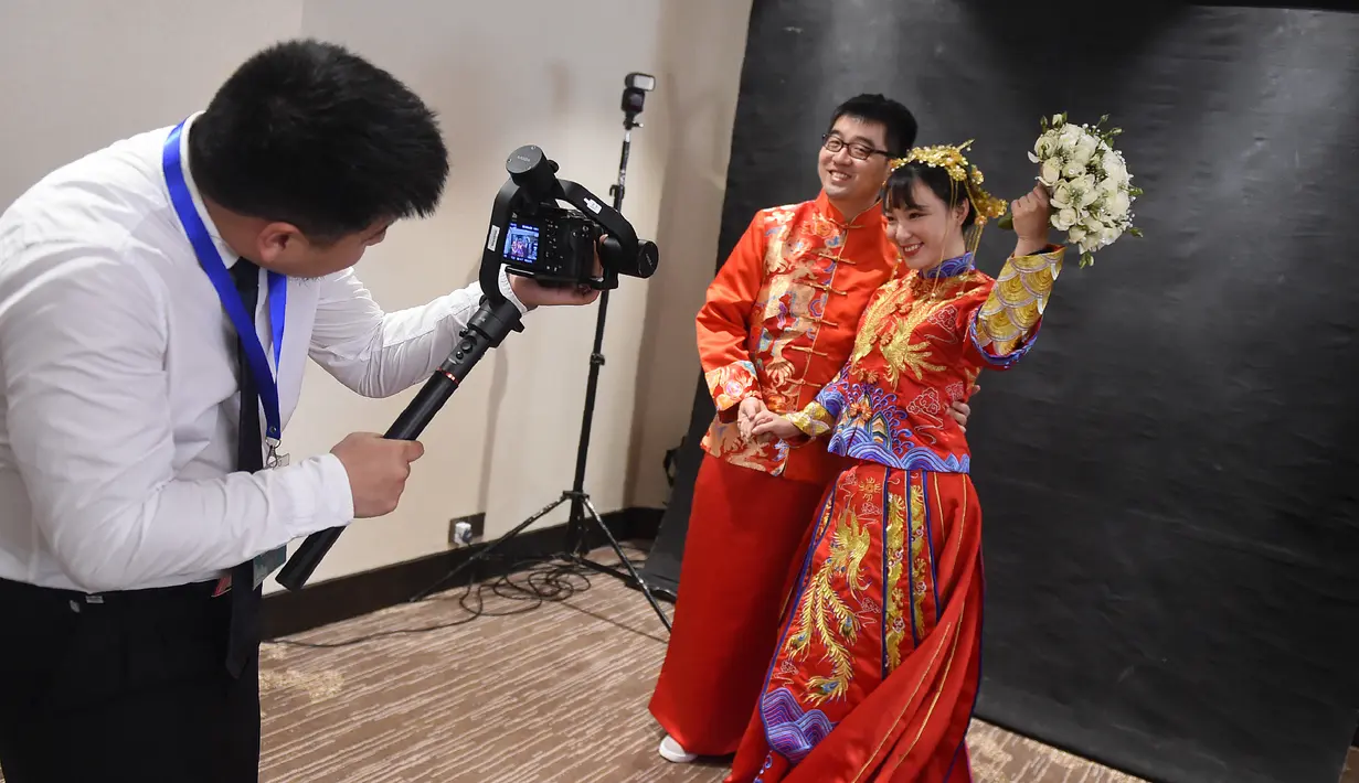 Pasangan pengantin asal Tiongkok mengenakan baju tradisional berfoto saat mengikuti pernikahan massal di Kolombo, Sri Lanka (17/12). Acara nikah massal ini juga bertujuan untuk meningkatkan pariwisata di Sri Lanka. (AFP Photo/Ishara S. Kodikara)