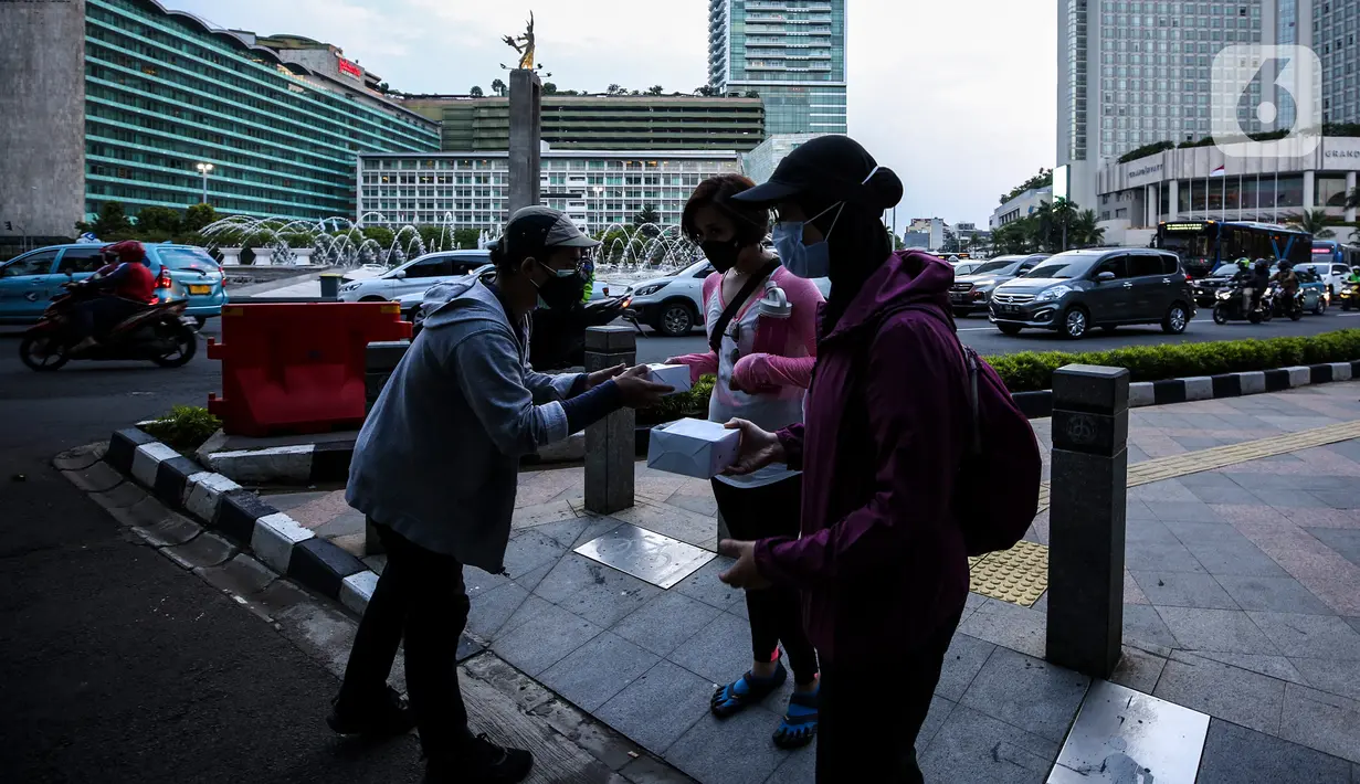 Suasana pembagian takjil kepada pejalan kaki di Kawasan Bundaran HI, Jakarta, Selasa (20/4/2021). Kegiatan berbagi takjil yang digagas oleh Pewarta Foto Indonesia Jakarta (PFIJ) ini dilaksanakan setiap hSelasa dan Jumat selama bulan Ramadhan sebagai bentuk solidaritas. (Liputan6.com/JohanTallo)