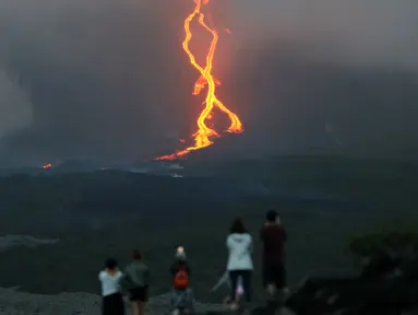 Warga melihat guguran lava pijar yang keluar dari gunung api Piton de la Fournaise atau Peak of the Furnace di Pulau Reunion, Samudera Hindia, Prancis, Selasa (13/8/2019). Letusan Piton de la Fournaise berlanjut hingga hari ketiga. (Richard BOUHET/AFP)