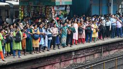 Penumpang menunggu kereta lokal tiba di Mumbai, India, Kamis (8/9/2022). Indian Railways dikatakan sebagai jaringan terbesar kedua di dunia. Di India umumnya menggunakan rel berukuran 1,676 mm atau rel lebar. (Indranil MUKHERJEE/AFP)