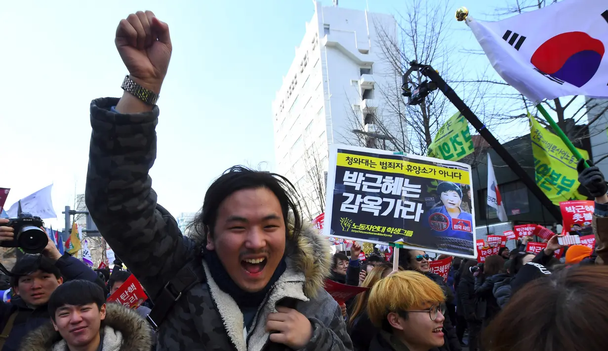 Aktivis anti-pemerintah bersorak setelah Presiden Korsel Park Geun-hye resmi dimakzulkan oleh Mahkamah Konstitusi di Seoul, Jumat (10/3). Presiden Park disebut sengaja membiarkan teman dekatnya, Choi Soon-Sil, mencampuri urusan negara. (JUNG Yeon-Je/AFP)
