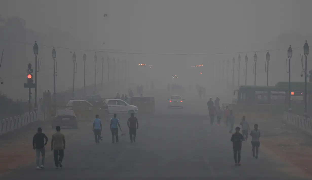 Pejalan kaki berjalan di tengah-tengah kondisi kabut asap tebal di New Delhi (2/11). Tingkat kabut melonjak selama musim dingin di Delhi, ketika kualitas udara melampaui tingkat aman Organisasi Kesehatan Dunia. (AP Photo/Money Sharma)