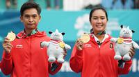 Petenis ganda campuran Indonesia Christopher Rungkat (kiri) dan Aldila Sutjiadi menggigit medali emas pada upacara penganugerahan medali seusai menang atas petenis Thailand Luksika Kumkhum dan Sonchat Ratiwatana pada final tenis ganda campuran Asian Games