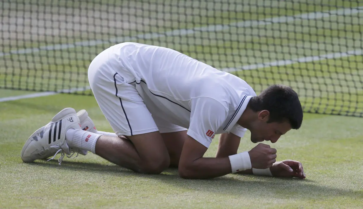 Setelah bertanding selama dua setengah jam, petenis Serbia itu meluapkan emosinya dengan berlutut dan makan sejumput rumput lapangan di depan 15.000 penonton, termasuk para selebriti, London, Minggu (6/7/14). (REUTERS/Suzanne Plunkett)