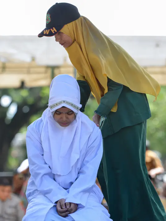 Polisi syariah menempatkan seorang karyawati bernama Nur Fadilah (21) saat akan dihukum cambuk karena mesum di Banda Aceh, Senin (29/10). Nur dan pasangannya divonis bersalah oleh Mahkamah Syariah Banda Aceh. (Chaideer Mahyuddin/AFP)
