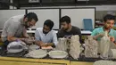 Desainer National Institute of Design (NID), Pravinsinh Solanki membimbing muridnya saat membuat karya seni dari uang kertas pecahan 500 dan 1.000 Rupee di Ahmedabad, India (26/4). (AFP PHOTO/SAM PANTHAKY)