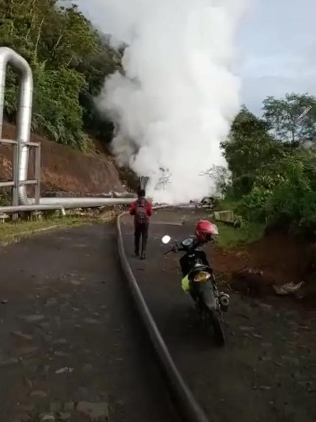Seorang warga terpaksa menepikan kendaraannya akibat akses jalan Tasikmalaya - Garut yang berada di PGE Area Karaha terputus material longsor, sekaligus merusak fasilitas pipa uap milik perusahaan.