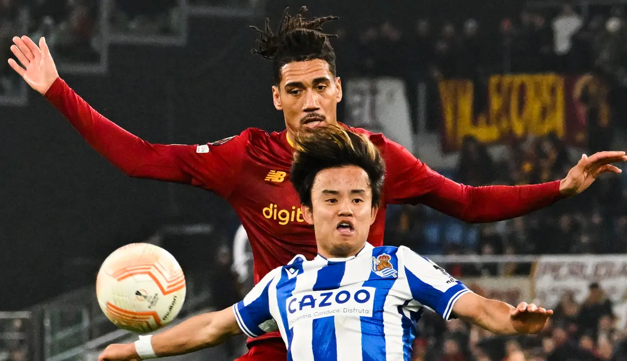 Penyerang Real Sociedad, Takefusa Kubo (Depan) dan bek AS Roma, Chris Smalling mengincar bola pada laga pertama babak 16 besar Liga Europa 2022/2023 di Olimpico, Jumat (10/3/2023) dini hari WIB. Berkat hasil ini, Roma pun berpeluang besar untuk lolos ke babak perempat final. (Photo by Alberto PIZZOLI / AFP)