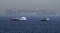 Dua perahu tradisional berlayar melewati sebuah kapal kontainer besar di Selat Hormuz, Jumat, 19 Mei 2023. (AP/Jon Gambrell)