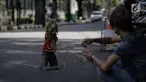 Seekor monyet melakukan aksi untuk menghibur warga di kawasan Abdul Rachman Saleh, Jakarta, Sabtu (31/3). Meski pertunjukkan ini dikritik masyarakat pecinta hewan, namun atraksi topeng monyet masih dijumpai di pinggir jalan. (Liputan6.com/Faizal Fanani)