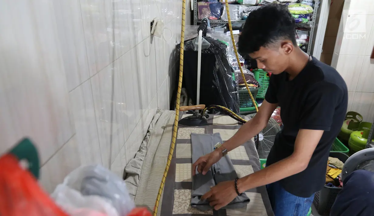 Pekerja menyeterika pakaian di toko laundry di Jakarta, Rabu (20/6). Libur lebaran banyak jasa laundry kebanjiran order hingga 100 karena banyaknya para pembatu rumah tangga yang mudik lebaran. (Liputan6.com/Angga Yuniar)
