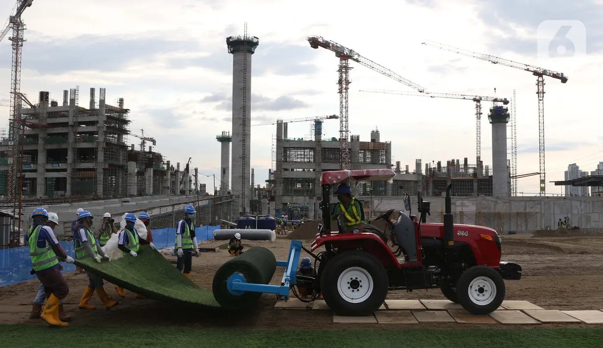 Pekerja melakukan pemasangan rumput di lapangan latih Jakarta International Stadium, Jumat (23/10/2020). Nantinya lapangan latihan ini akan ditumbuhi rumput hybrid, yang memiliki komposisi 5 persen rumput sintetis dan 95 persen natural berjenis Zoysia Matrella. (Liputan6.com/Helmi Fithriansyah)