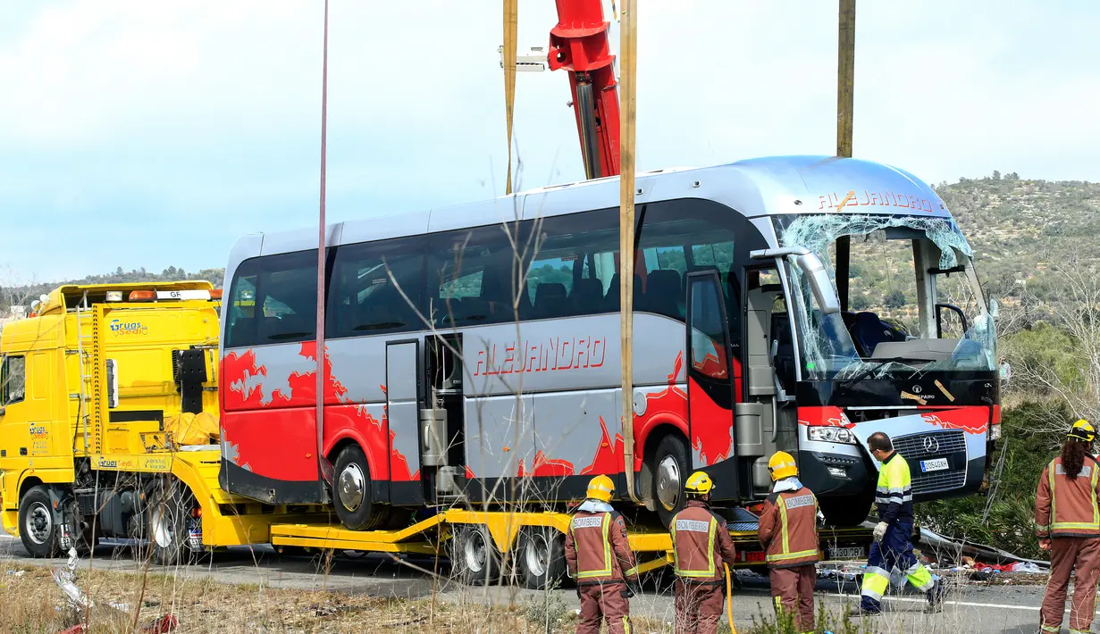 Petugas menggunakan crane untuk memindahkan bangkai bus ke truk tailer di Jalan Raya AP7 dekat Kota Freginals, Spanyol, Minggu (20/3). Bus berisi 57 mahasiswa asing itu terbalik ketika dalam perjalanan dari Valencia menuju Barcelona (PAU Barrena/AFP)
