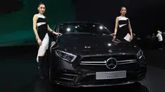 Dua model berpose di samping Mercedes Benz CLS 53 2019 selama Thailand International Motor Expo di Bangkok (29/11). Thailand International Motor Expo bertema “Enjoy Driving! Before Driverless Era”.  (AFP Photo/Lillian Suwanrumpha)