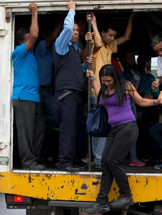 Seorang wanita turun dari truk kargo yang berfungsi sebagai transportasi umum di Villa de Cura, Venezuela, Senin (22/1). Pemilik truk lebih suka membawa penumpang daripada barang dagangan karena penjarahan kian marak. (AP Photo/Fernando Llano)